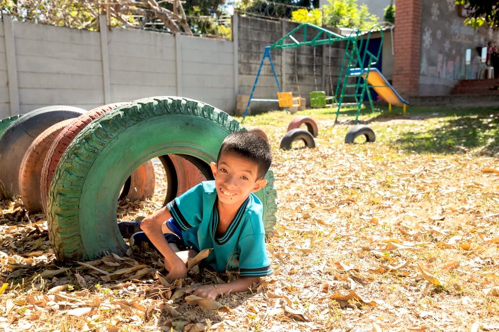 Levi plays on the playground, crawling through colourful tires